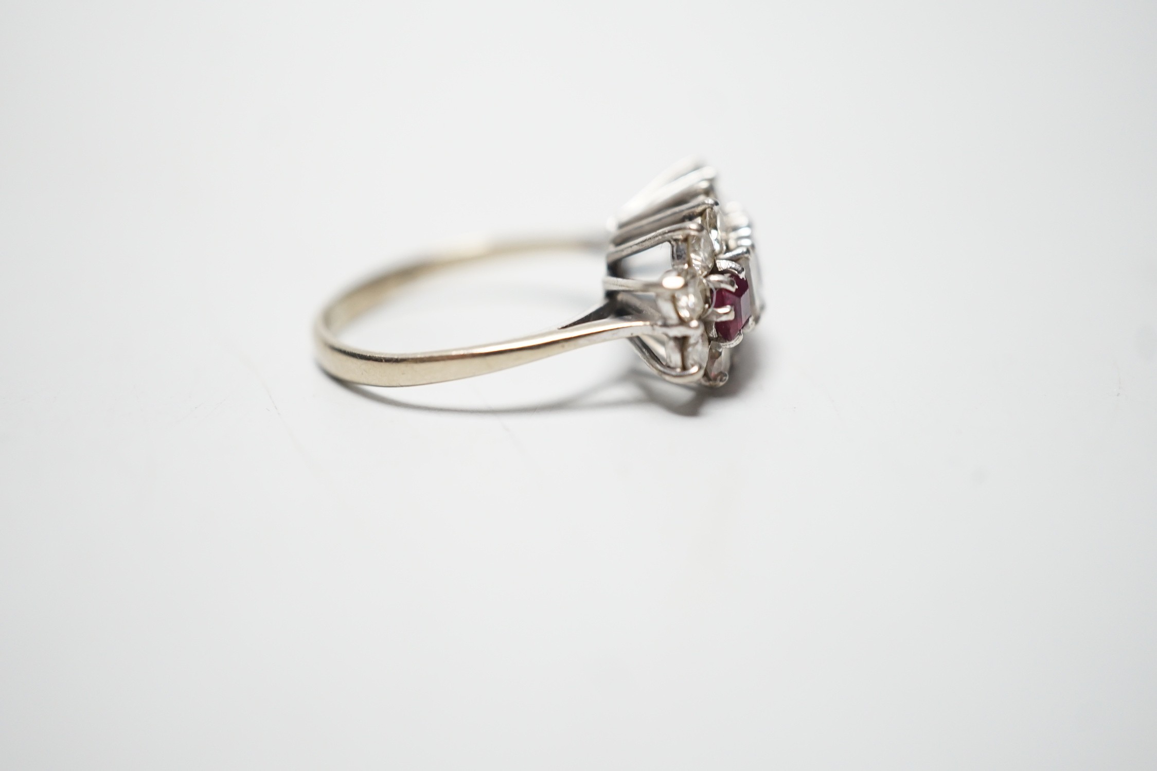 A modern 18ct white gold, square cut ruby and round and baguette cut diamond set cluster ring, size L, gross weight 3.9 grams.